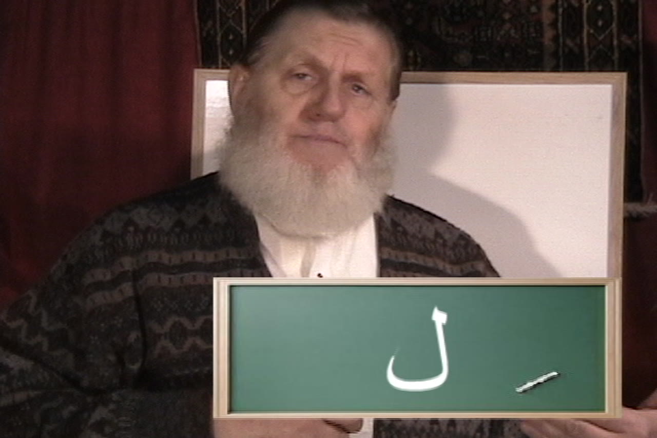 Yusuf Estes holding up an Arabic letter card